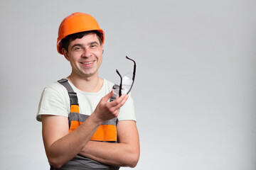 Wall Mural - Young cheerful,carefree builder constructor in hard hat and overalls on studio background, building industry concept