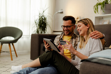 Cute Caucasian sitting on the floor and using tablet for online shopping. Woman holding credit card.