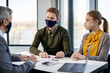 © Drazen - Couple wearing face masks while going through housing plans with real estate agent during the meeting.