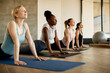 © Drazen - Multi-ethnic group of athletic women doing stretching exercise on Yoga class at health club.