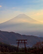 View of the silhouette of a torii gate with Mount Fuji visible in the background at dusk