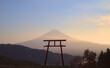 Late afternoon view of the silhouette of a torii gate with Mount Fuji visible in the background