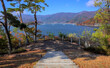 View of paved steps leading down to a small observation platform overlooking Lake Kawaguchi and some surrounding forested mountains on a sunny autumn day