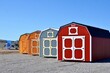 Colorful wooden sheds on display. American shed is typically a simple, single-story roofed structure in a back garden or on an allotment that is used for storage, hobbies, or as a workshop.	
