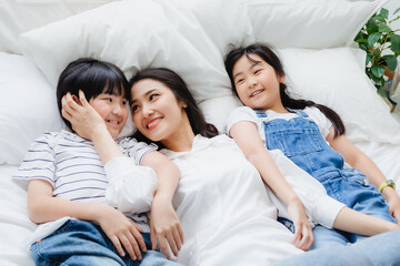 Poster - Happy Asian family smiling mother, son & daughter on bed in bedroom. Mom, son & daughter have fun together at home. Love relationship or bonding between mum and children. People lifestyle concept