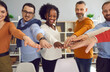 © Studio Romantic - Humanism and social responsibility, business training and corporate coaching session concept. Group of diverse multiracial people different age holding hands joining together front view shot