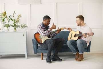 African man and Caucasian man playing guitar