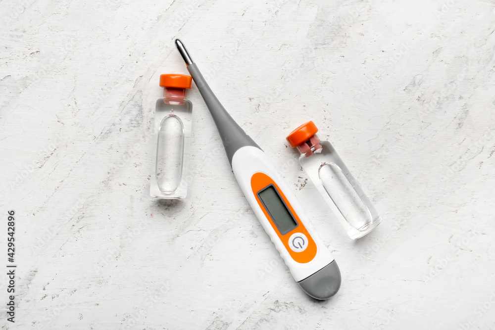 Electronic thermometer with vaccine on white background