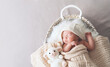 Sleeping newborn baby in basket wrapped in blanket in white fur background. Portrait of little child one week old with soft toys.