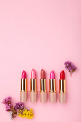 Wall Mural - Lipstick with beautiful flowers on pink background with copy space. Vertical foto