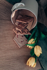 Handmade pink chocolate with raspberries. Vegetarian chocolate with berries on a wooden table and pink paper. A pink little bucket with yellow yellow in it. International Women's Day on March 8.