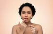 © Syda Productions - beauty, make up and cosmetics concept - beautiful young african american woman applying lip gloss with finger over beige background