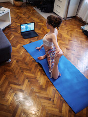 one young woman, exercising yoga at home, in room using yoga mat.