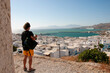 Young tourist observes the panorama of the village of Chora on the island of Mykonos in Greece. In the background the roofs of the white houses and the Aegean Sea.