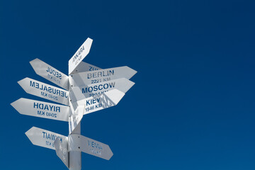 White metal signpost or street sign indicating directions to different places of the world