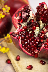 ruby red, juicy pomegranate open on a table with apple and dry yellow flowers