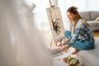 © NDABCREATIVITY - Creative beautiful woman painting at home. Coronavirus quarantine, isolation.
