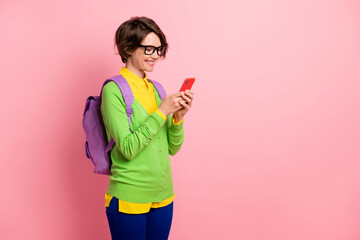 Poster - Photo of lady dressed yellow shirt glasses backpack holding looking modern device empty space isolated pink color background