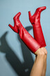 Female legs wearing red boots over blue sky wall