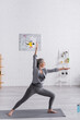 © LIGHTFIELD STUDIOS - middle aged woman in sportwear standing in warrior pose while practicing yoga