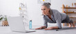 © LIGHTFIELD STUDIOS - mature woman doing plank and looking at laptop, banner