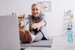 © LIGHTFIELD STUDIOS - mature woman with grey hair stretching on yoga mat near sports bottle