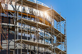 Fototapeta  - Extensive scaffolding providing platforms for work in progress on a new apartment block,Tall building under construction with scaffolds,Construction Site of New Building