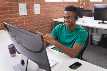 African american businessman having video call sitting in front of computer using headphones