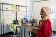 © wavebreak3 - Happy african american businesswoman looking at glass wall with sticky notes