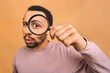 Curious young african american black man with magnifying glass Isolated over beige background. Surprised young man student holding magnifying glass.