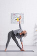 © LIGHTFIELD STUDIOS - middle aged woman standing in triangle pose while practicing yoga on mat at home