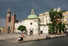 The Main Market Square With  Romanesque Church Of St. Wojciech And Famous St. Mary's Basilica With Two Towers In Krakow, Poland