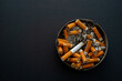 © Praewphan - Close up many cigarette butts in full and dirty  ashtray isolated on black background copy space for text design