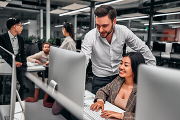 two colleagues work together. a man shows work on a computer screen. business people discuss project