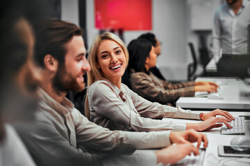 Young adult business people working on computers with colleagues in a spacious office. Data analysis, statistics, finance. Training, business team, programming, development. Computer work.