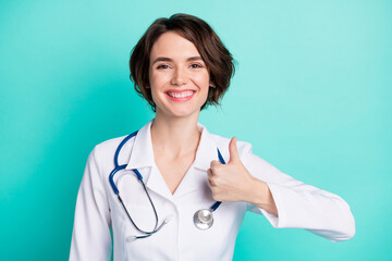 Canvas Print - Photo of young woman happy positive smile nurse clinic show thumb-up fine cool ad advice isolated over turquoise color background