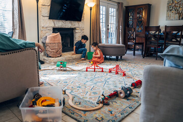 Wall Mural - Boy and girl playing with toy train in living room