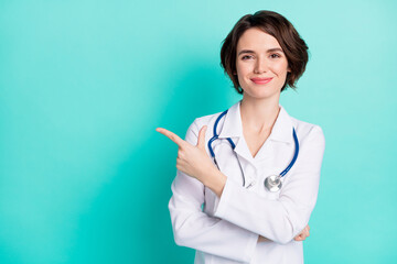 Photo of young woman surgeon happy smile indicate finger empty space advert advice decision isolated over teal color background