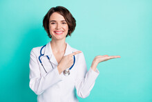 Photo Of Young Woman Doctor Happy Smile Indicate Finger Product Promo Offer Advert Isolated Over Teal Color Background