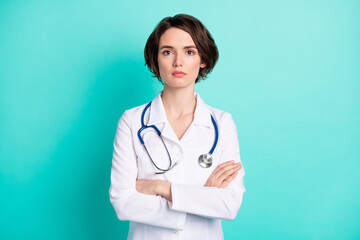 Sticker - Photo of young woman serious confident crossed hands doctor surgeon clinic isolated over teal color background