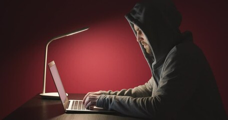 Programmer working on laptop at table against color background