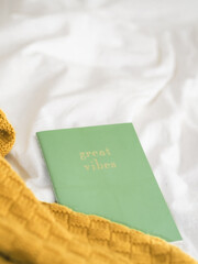 Sticker - Vertical shot of a green notebook with a text 'great vibes' on a white cloth