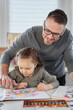 © boytsov - Happy art creative leisure activity. Beautiful caring art or drawing teacher in eyeglasses help to draw cute preschool girl sitting at the table, teacher enjoy helping small kid doing drawing at home