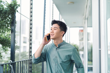 Wall Mural - A portrait of man standing at a balcony making a phone call.