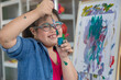 © Bangkok Click Studio - Happy girl with Down syndrome painting on easel