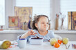 © boytsov - Funny laughing girl is having dinner sitting at the table stuffed mouth with food. Small cute schoolgirl having lunch. Eating using fork from lunch box. Tasty eating concept. High quality image