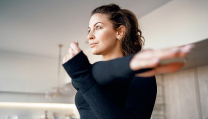 Wall Mural - Athletic figure and lifestyle. Exercises for stretching the muscles before starting the sport. A female coach conducts a training session at home.