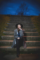 Sticker - Young female in casual clothing and a hat posing on the stairs at night