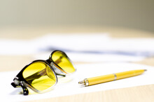 Yellow Glasses For Working On A Computer Are On The Table Next To A Fountain Pen