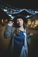 Poster - Young female in casual clothing and a hat posing in the city at night